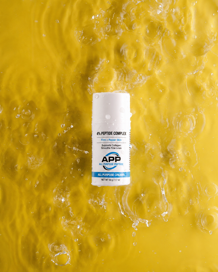 A white cylindrical bottle of APP Labs 4% Peptide Complex serum, surrounded by splashing water droplets on a vibrant yellow background.